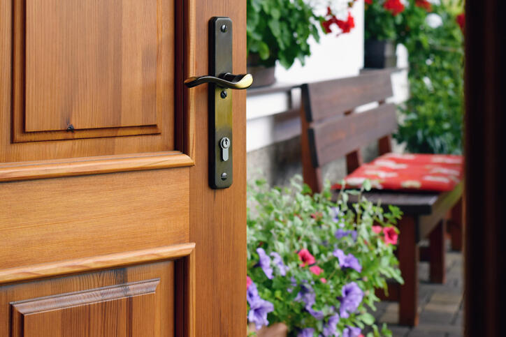 Half opened door into the beautiful summer terrace and blooming garden