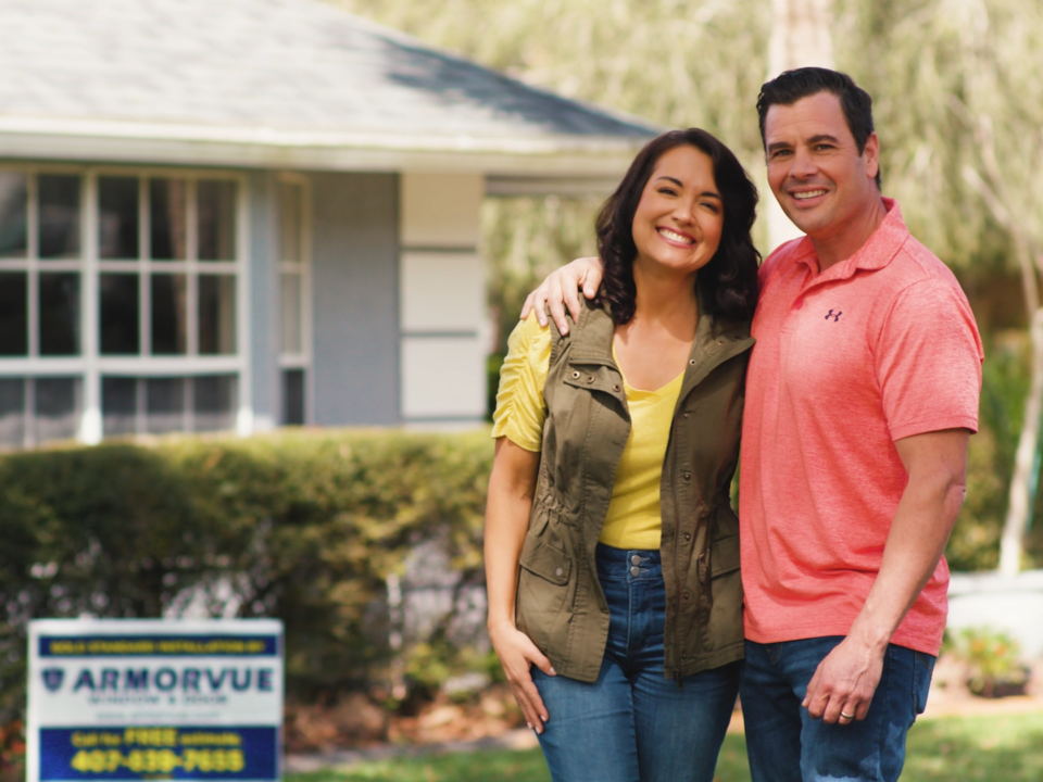 Happy young couple standing in front of their home after booking an ARMORVUE showroom appointment.