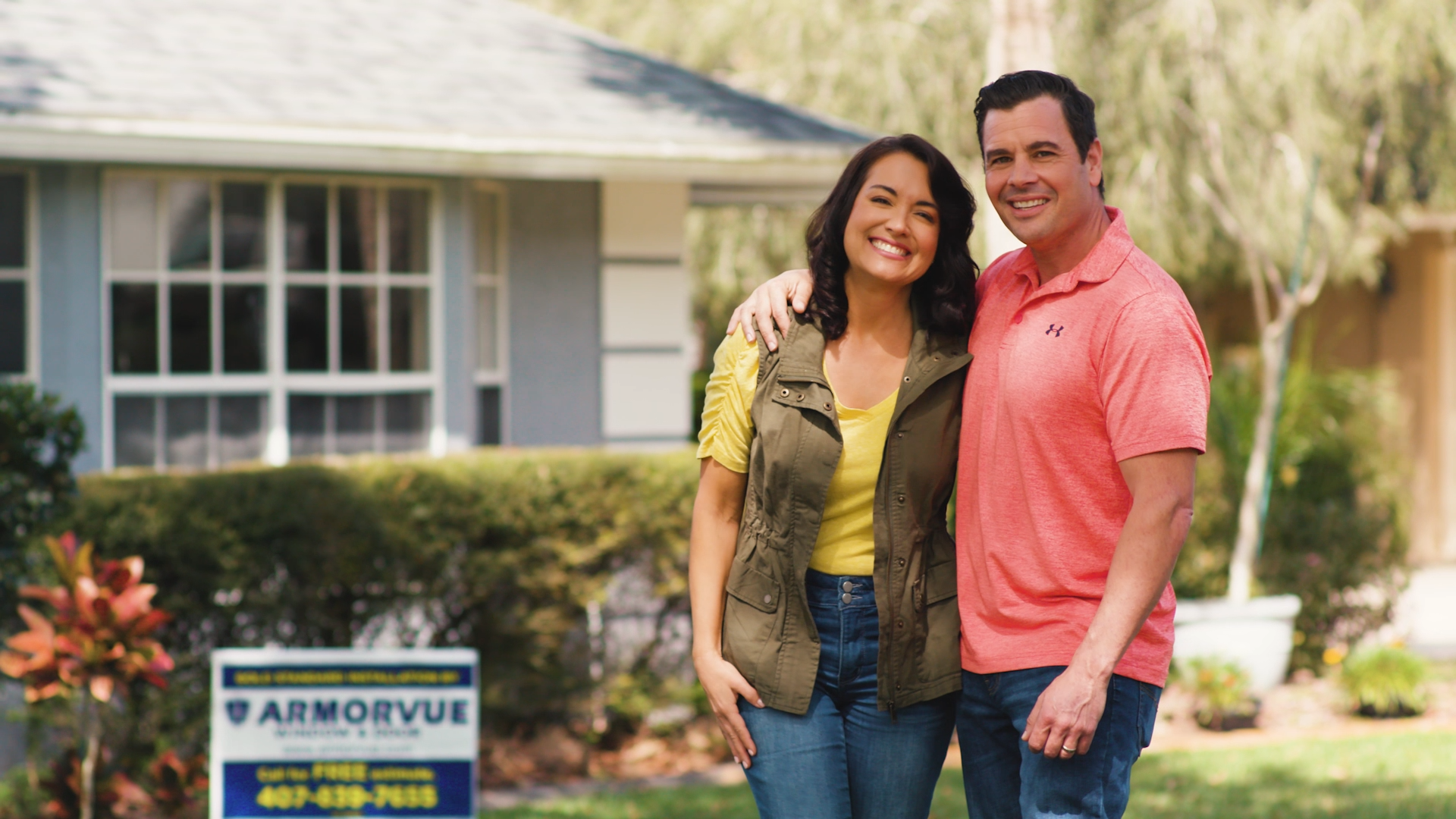 Happy young couple standing in front of their home after booking an ARMORVUE showroom appointment.