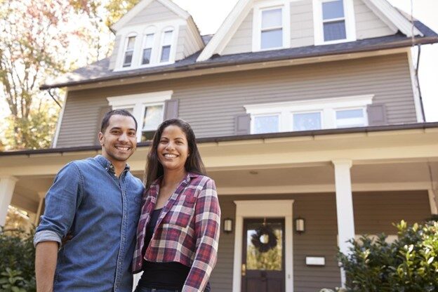 Happy young couple standing in front of their home after booking an ARMORVUE showroom appointment.